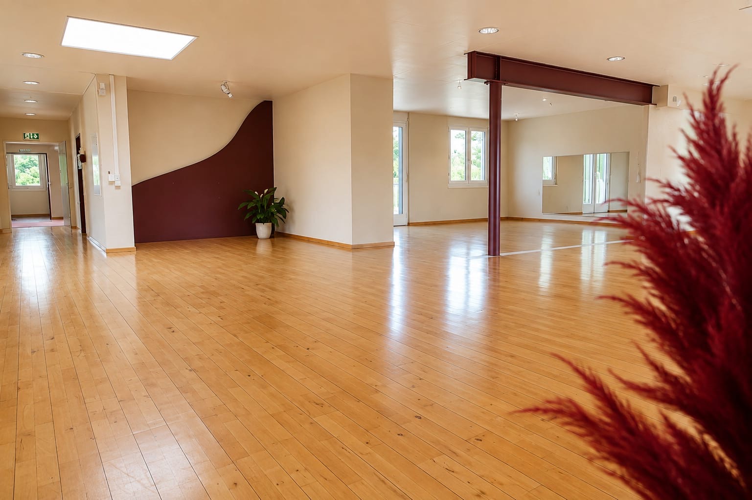 Hauptsaal des PULSANA Studios in Gipf-Oberfrick mit Holzparkett und burgunderfarbenen Wandelementen